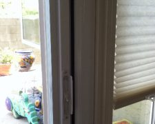 WHITE ROLL-AWAY SCREEN DOOR FLUSH WITH DOOR MOULDING ON DOOR THAT SWINGS OUT
