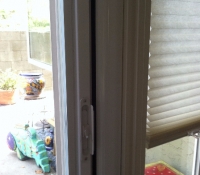 WHITE ROLL-AWAY SCREEN DOOR FLUSH WITH DOOR MOULDING ON DOOR THAT SWINGS OUT