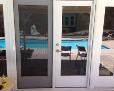 WHITE FRENCH ROLL-AWAY SCREEN DOORS WITH FIXED DOOR LOCKED IN PLACE
